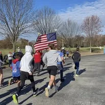 Runners sprinting while carrying an American flag
