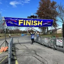 A runner raising her arms as she crosses the finish line