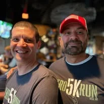 Two friends posing together in Hero Run shirts