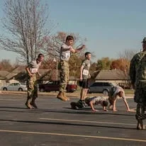 Kids jumping over a participant at a battle station